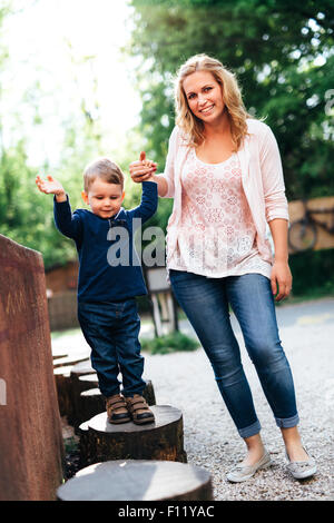 Giovane e bella madre e il suo bambino per mano per esterno Foto Stock