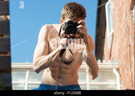 Ma povero uomo muscolare con la sua parte superiore a scattare foto di se stesso in uno specchio. Abstract scatti. Lo specchio è la posa sull'erba. Foto Stock