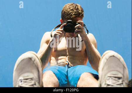 Ma povero uomo muscolare con la sua parte superiore a scattare foto di se stesso in uno specchio. Abstract scatti. Lo specchio è la posa sull'erba. Foto Stock