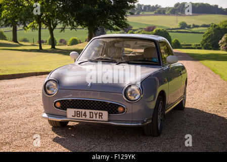 Nissan Figaro vintage automobile parcheggiata nel giardino di una dimora signorile, Inghilterra, Regno Unito. Foto Stock