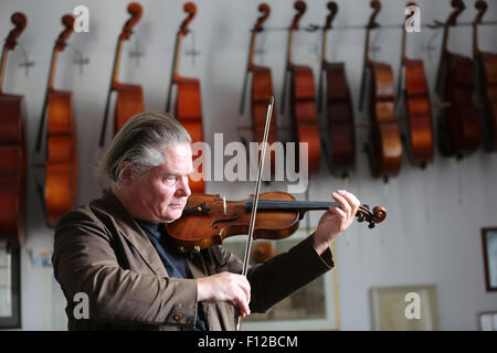 Berlino, Germania. 21 Ago, 2015. Liutaio Florian Friedrich Lehmann tunes un strumento riparato presso la sua officina a Berlino, Germania, 21 agosto 2015. Il 57-anno-vecchio ha circa 200 strumenti restaurato in vendita presso la sua officina in Berlin-Mitte. Foto: Wolfgang Kumm/dpa/Alamy Live News Foto Stock