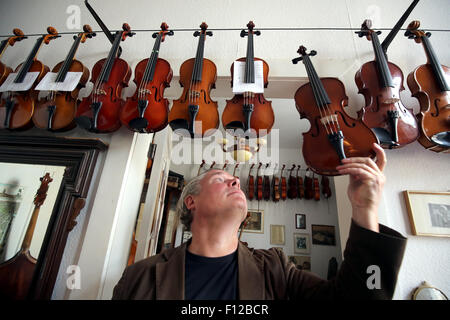 Berlino, Germania. 21 Ago, 2015. Liutaio Florian Friedrich Lehmann riaggancia un riparato e ripristinato strumento nel suo laboratorio di Berlino, Germania, 21 agosto 2015. Il 57-anno-vecchio ha circa 200 strumenti restaurato in vendita presso la sua officina in Berlin-Mitte. Foto: Wolfgang Kumm/dpa/Alamy Live News Foto Stock
