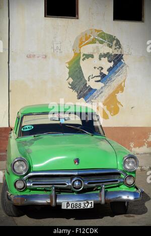 Vintage Ford verde taxi parcheggiato al di sotto di Che Guevara murale nel parcheggio a l'Avana Vecchia Cuba Foto Stock