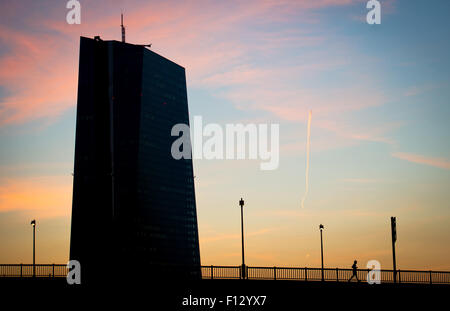 La Banca centrale europea sta in piedi di fronte ad un colorato cielo mattutino, un pareggiatore corre da in Frankfurt/Main, Germania, 26 agosto 2015. Foto: Christoph Schmidt/dpa Foto Stock