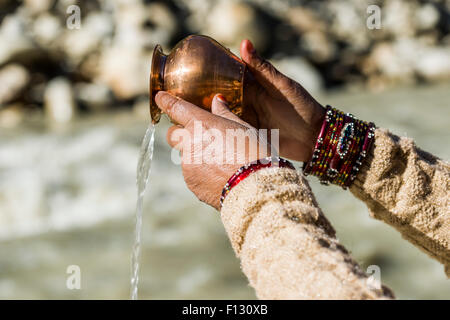 Una femmina di pellegrino pregando, offrendo l'acqua santa, sulle rive del fiume Gange, Gangotri, Uttarakhand, India Foto Stock