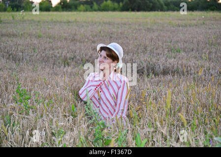 Un pensieroso donna su un campo di grano Foto Stock