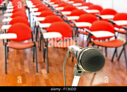 In prossimità del microfono nella parte anteriore delle sedie vuote in sala conferenze Foto Stock