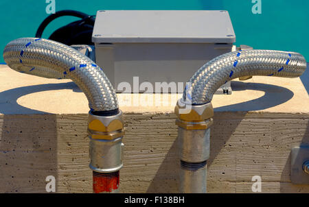 I tubi in acciaio galvanizzato montato su di un muro di cemento con i suoi rubinetti Foto Stock