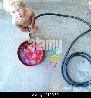 Il Toddler riempire un secchio con acqua Foto Stock