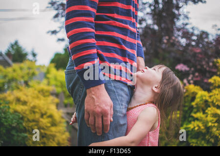 Figlia di padre di contenimento per le gambe, guardando verso l'alto Foto Stock