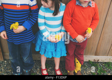 Tre bambini in piedi in fila con fiori Foto Stock