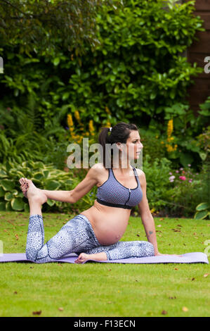 Donna incinta fare yoga in giardino Foto Stock