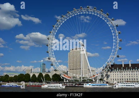 Il London Eye (Millenium) ruota sul fiume Tamigi con crociera fluviale artigianato in primo piano - South Bank di Londra Foto Stock