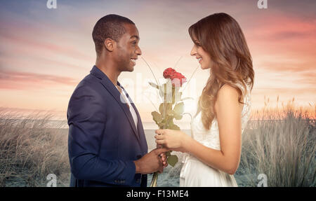 Sorridente romantico bello giovane africano propone per la sua amata come egli innesti un mazzetto di alto fusto rose rosse nella sua Foto Stock