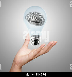 La mano che mostra 3d di metallo del cervello umano in una lampadina elettrica come concetto creativo Foto Stock