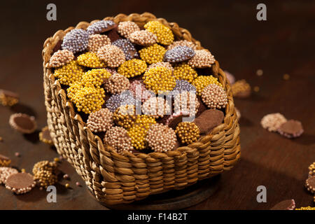 Colorati confetti di cioccolato messi in cesto su uno sfondo di legno Foto Stock