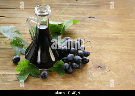 Aceto balsamico in una caraffa di vetro con uve fresche Foto Stock