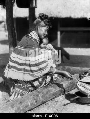 1920s nativi americani donna SEMINOLE tenendo il bambino e la cottura di Florida USA Foto Stock