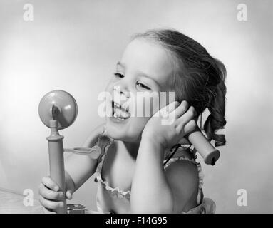 Anni Cinquanta felice bambina parlando in TOY TELEFONO Foto Stock