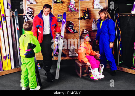 Famiglia nel negozio di sci papà figlio guardare AY SKI MOM figlia cercando su scarponi Foto Stock