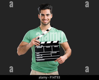 Ritratto di bel giovane tenendo un clapboard, isolata su uno sfondo grigio Foto Stock