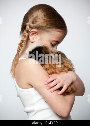 La ragazza (6-7) abbracciando la cavia, studio shot Foto Stock