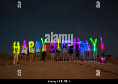 Time Lapse vista di amici la scrittura di buon compleanno sul deserto remoto collina sotto il cielo stellato Foto Stock