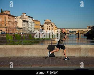 L'Italia, Firenze, uomo maturo jogging, Ponte Vecchio in background Foto Stock