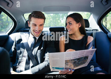 Coppia felice leggendo il giornale in auto Foto Stock