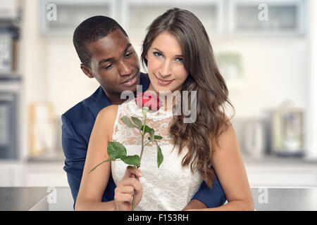 Bello nero americano fidanzato abbracciando la sua graziosa Ragazza con rose e fiori sorridenti alla fotocamera, in piedi la kitc Foto Stock