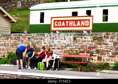 Goathland rail station segno persone in attesa per il prossimo treno banco carrello North Yorkshire Regno Unito Inghilterra sat seduto seduta salotto Foto Stock