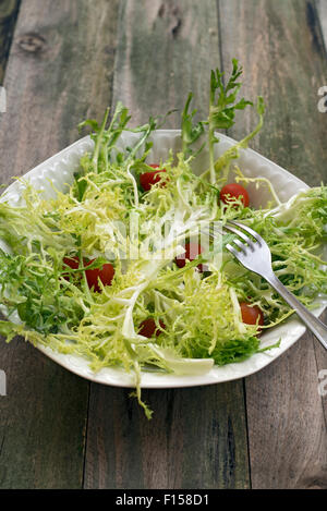 Insalata di indivia, conditi con olio di oliva e guarnito con pomodorini Foto Stock