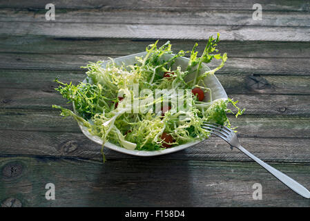 Insalata di indivia, conditi con olio di oliva e guarnito con pomodorini Foto Stock