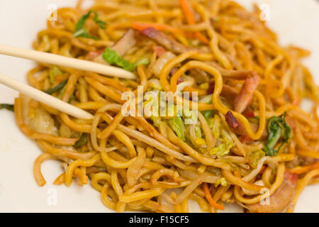 Mangiare carne di maiale cinese lo mein tagliatelle con bacchette Foto Stock