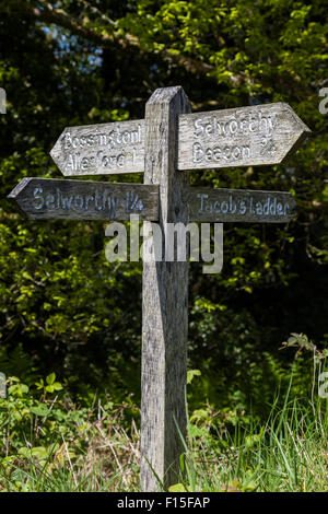 Weathered indicazioni del cartello in legno che indica sentieri pubblici per Selworthy, Selworthy Beacon, Jacobs scaletta, Bossington e Allerford. Foto Stock