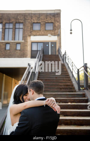 Ritratto di sposa e lo Sposo abbracciando in fondo alla scalinata all'aperto, Hamilton, Ontario, Canada Foto Stock
