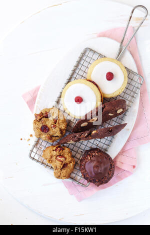 Varietà di biscotti sani sul filo di un raffreddamento per rack con un bianco, tagliere e un tovagliolo rosa, studio shot su sfondo bianco Foto Stock