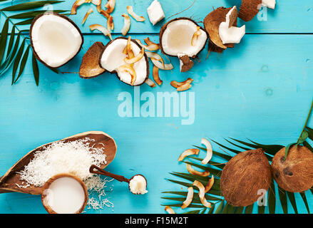 Latte di cocco, tutta la noce di cocco, olio di noce di cocco e noce di cocco tostato, studio shot su sfondo turchese Foto Stock