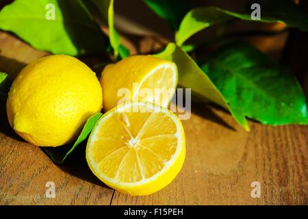 Fresche limone a fettine di limone e foglie di albero su un tavolo di legno. Foto Stock