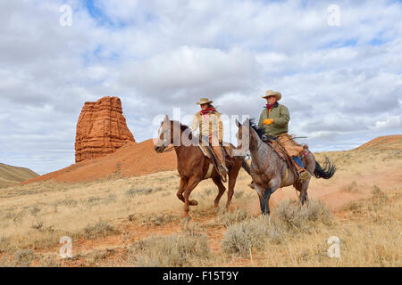 Cowboy e Cowgirl cavalli da sella con Castel Rock in background, Shell, Wyoming USA Foto Stock
