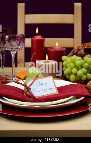 Felice ringraziamento impostazione tabella nel classico stile rustico di colori su tavola di legno con cornucopia centrotavola, candele e frutta. Foto Stock