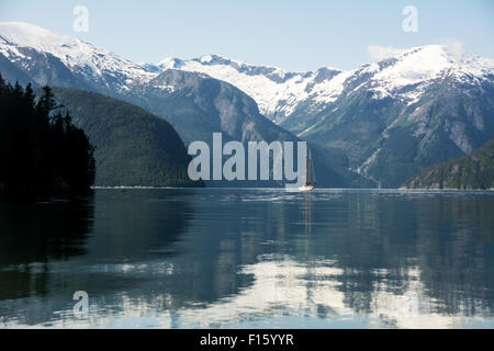 Una goletta ancorata al di sotto del Pacifico fiordo costiera nel grande orso nella foresta pluviale, British Columbia, Canada. Foto Stock