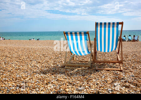 Due sedie a sdraio sulla spiaggia di fronte al mare, Brighton, Regno Unito Foto Stock