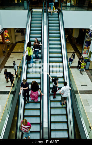 Persone su scale mobili in un centro commerciale per lo shopping Foto Stock