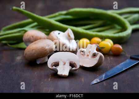 Funghi, pomodori e fagioli runner su una tavola di legno. Foto Stock