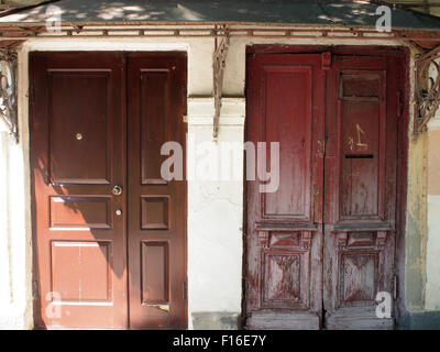 Due porte closeup - vecchio brown porta di legno e di un marrone nuova porta di ferro si trova accanto a uno sotto il portico Foto Stock