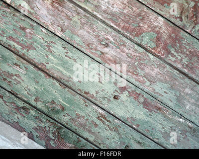 Dettaglio di un vecchio diagonal staccionata in legno con resti di vernice verde sulla mangy schede scuro con fessure per l'uso come backgrou Foto Stock