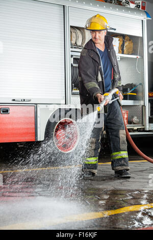 Fireman spruzzare acqua sul pavimento durante la pratica Foto Stock