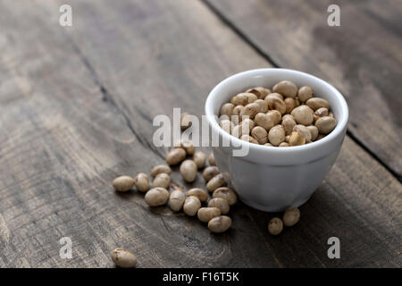 Arrosto di fagioli di soia in un recipiente su sfondo di legno Foto Stock