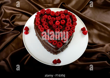 Valentines torta al cioccolato a forma di cuore decorata con lamponi Foto Stock